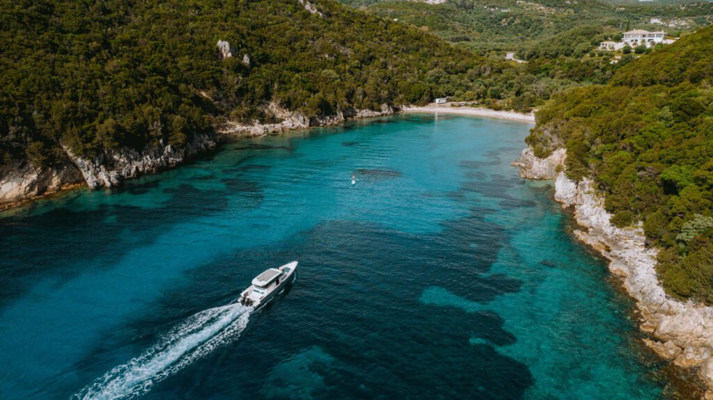 Overhead drone shot of the Axopar 37 cruising past rocky coves and green hills