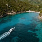 Overhead drone shot of the Axopar 37 cruising past rocky coves and green hills