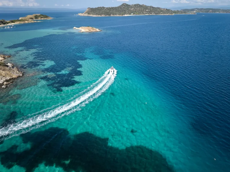 Aerial view of a private boat cruising the turquoise waters near Ammouliani and Drenia Islands, Ouranoupoli, Halkidiki